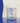 A blue swirl background and a front on product shot of our white frosted glass Boquet bottle and it's reflection on the table.