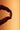A close up silhouette of a finger and thumb holding a Boquet pill against an orange background.