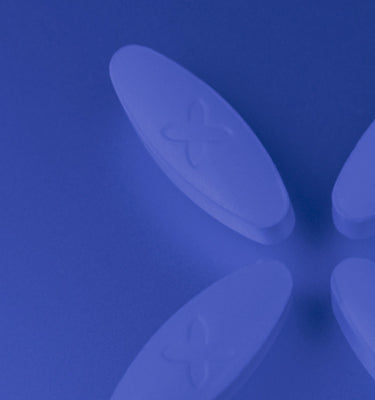 A blue background and 4 white oval Boquet suppository pills in a criss cross position to the right